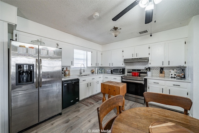 kitchen featuring white cabinetry, appliances with stainless steel finishes, decorative backsplash, and light wood-type flooring