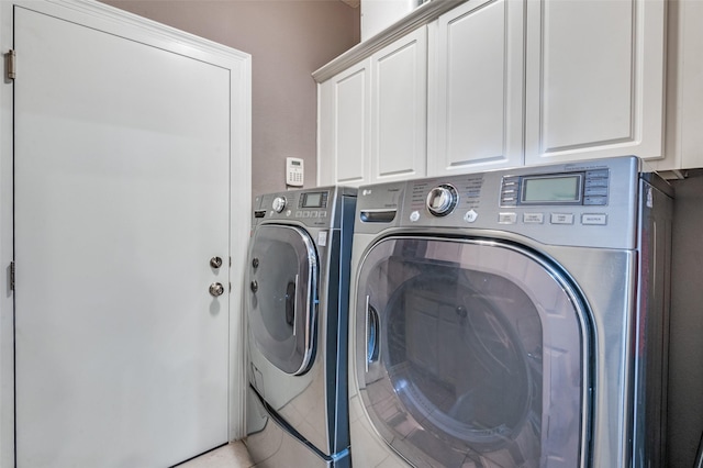 clothes washing area featuring washing machine and dryer and cabinets