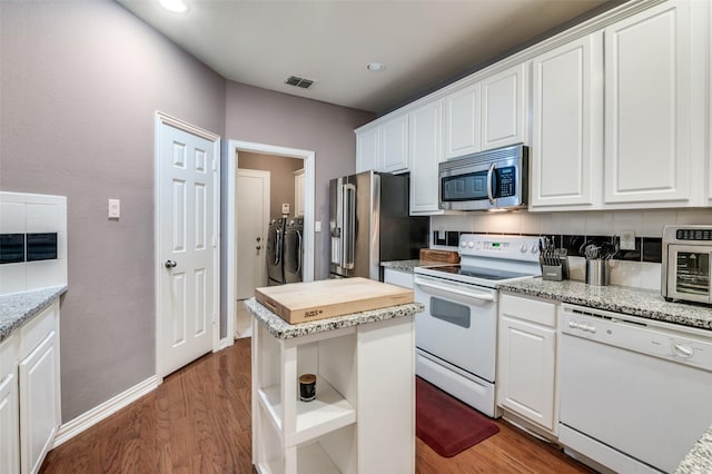 kitchen with stainless steel appliances, a center island, washing machine and dryer, and white cabinets