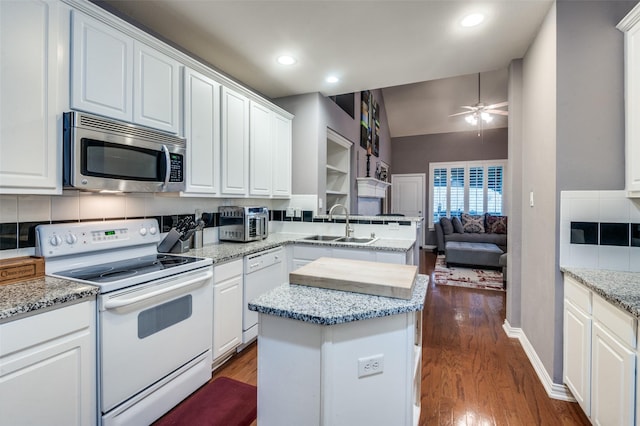 kitchen featuring sink, white appliances, white cabinets, a kitchen island, and decorative backsplash