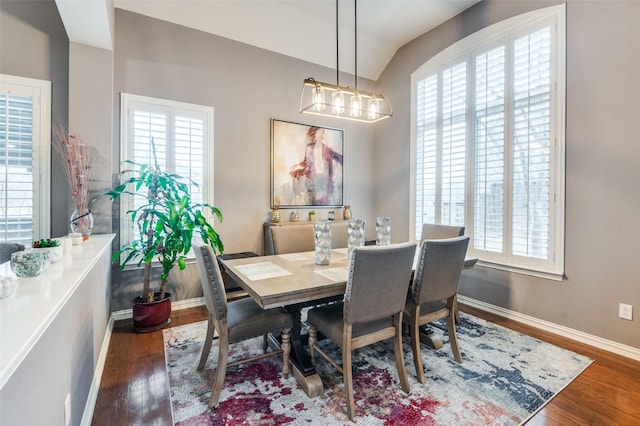 dining area with wood-type flooring, vaulted ceiling, and an inviting chandelier