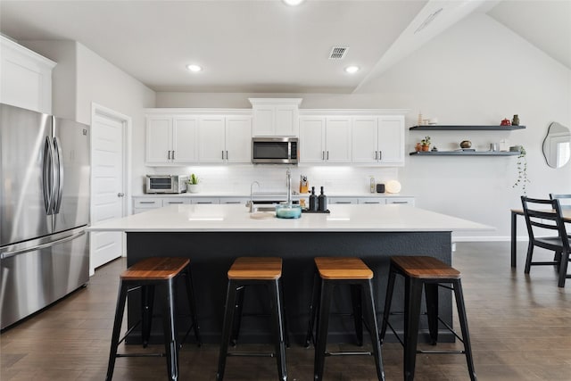 kitchen with visible vents, stainless steel appliances, a kitchen bar, and decorative backsplash