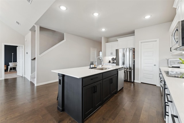 kitchen with white cabinets, appliances with stainless steel finishes, a kitchen island with sink, light countertops, and a sink