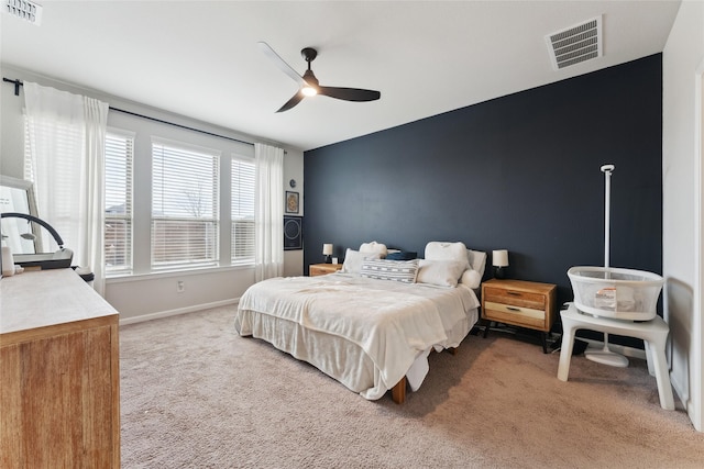 bedroom featuring light carpet, baseboards, an accent wall, and visible vents