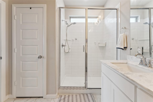 bathroom with marble finish floor, a shower stall, and vanity