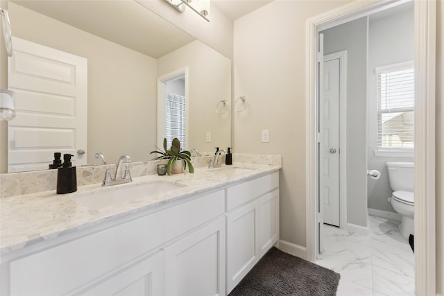 full bathroom with marble finish floor, double vanity, a sink, and toilet