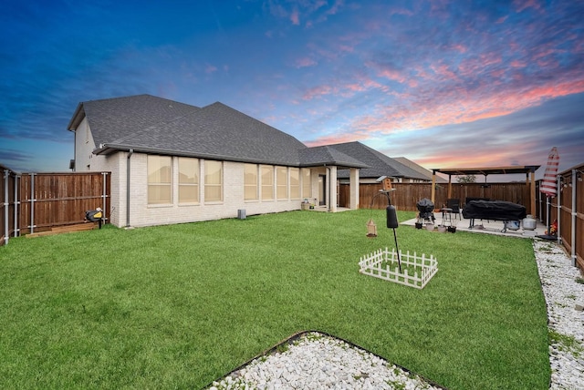 yard at dusk with a patio area and a fenced backyard