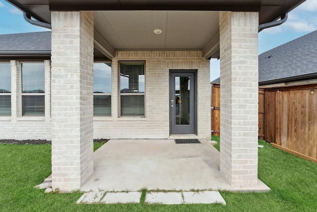 entrance to property with brick siding, fence, and a patio