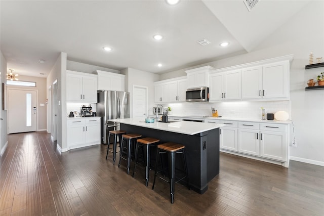 kitchen with stainless steel appliances, light countertops, a kitchen island with sink, and white cabinetry