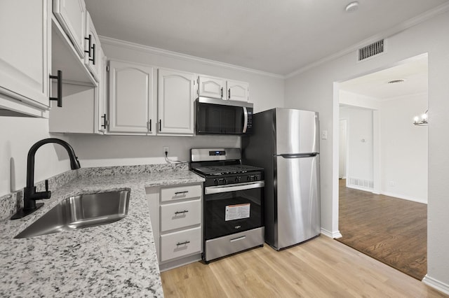 kitchen featuring sink, white cabinetry, ornamental molding, appliances with stainless steel finishes, and light stone countertops