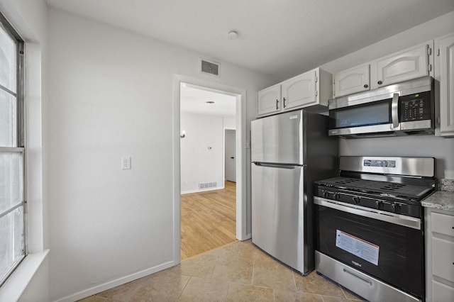 kitchen with white cabinetry, stainless steel appliances, and light tile patterned flooring