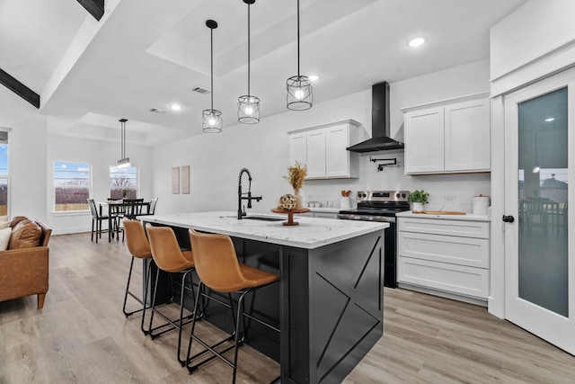 kitchen with decorative light fixtures, stainless steel electric range, a raised ceiling, wall chimney range hood, and white cabinets