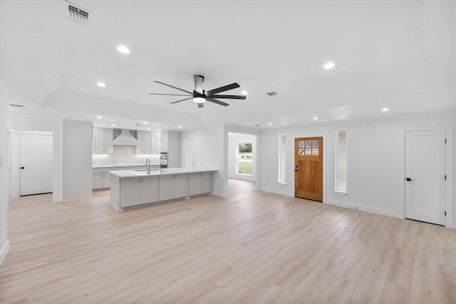 kitchen featuring ceiling fan, sink, custom exhaust hood, and light hardwood / wood-style flooring