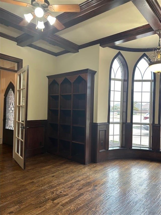 empty room with a wainscoted wall, dark wood-style flooring, and beamed ceiling