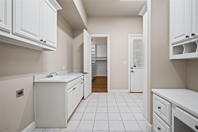 105 Zephyr Ct, Aurora, TX 76078 - laundry area featuring light tile patterned floors, cabinet space, hookup for an electric dryer, a sink, and baseboards