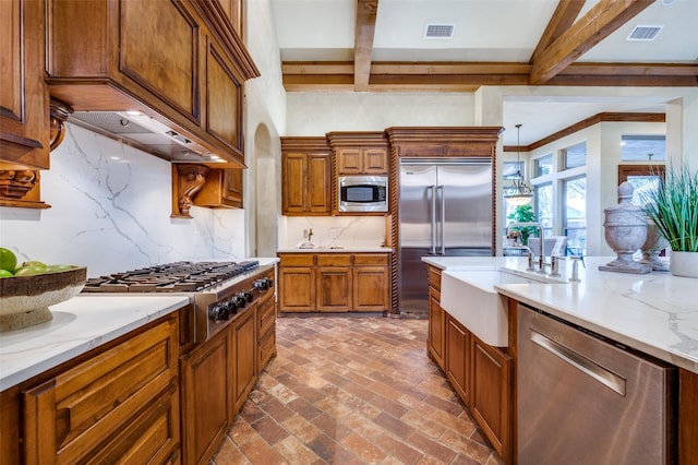 kitchen featuring pendant lighting, sink, beam ceiling, built in appliances, and decorative backsplash