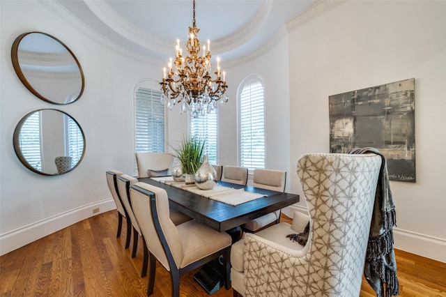 dining room featuring crown molding, hardwood / wood-style floors, a tray ceiling, and a notable chandelier