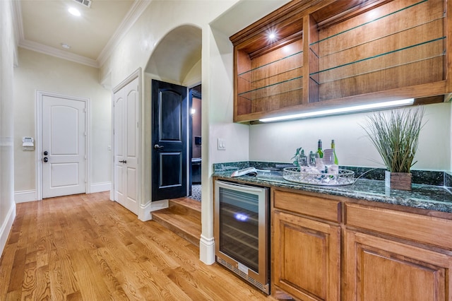 kitchen with crown molding, dark stone countertops, wine cooler, and light hardwood / wood-style flooring