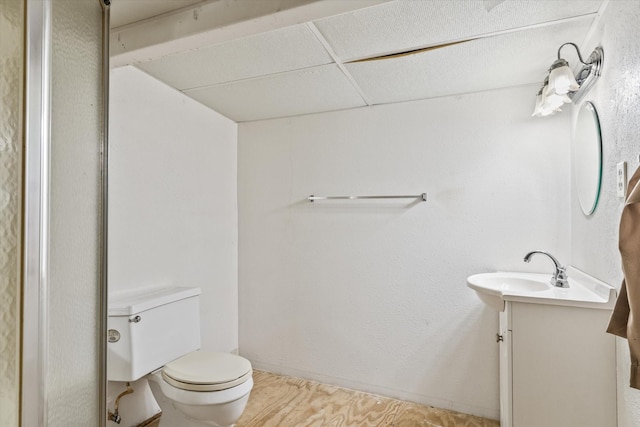 bathroom featuring vanity, toilet, and a drop ceiling