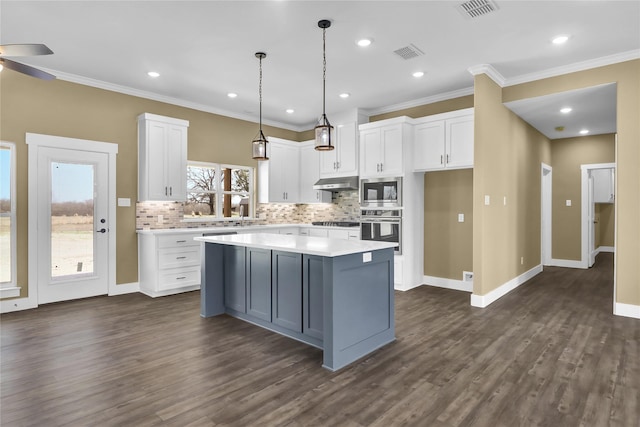 kitchen featuring stainless steel appliances, a kitchen island, dark wood-type flooring, and white cabinets