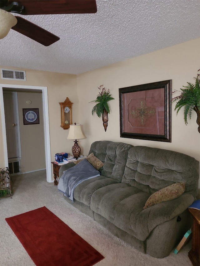 living room with a textured ceiling, carpet floors, and ceiling fan