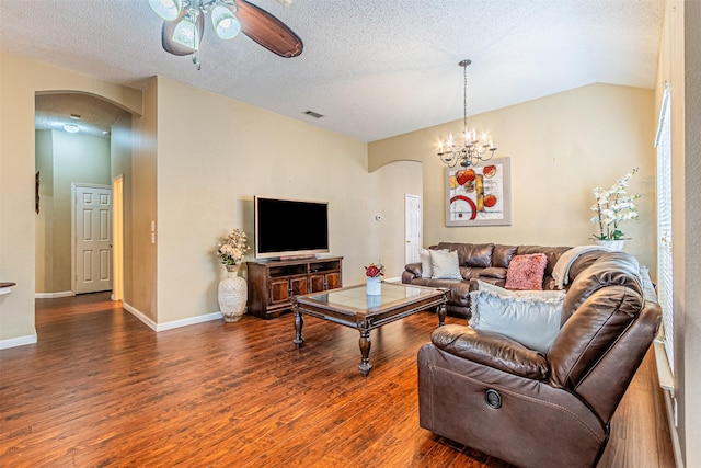 living room with dark wood-type flooring, lofted ceiling, ceiling fan with notable chandelier, and a textured ceiling