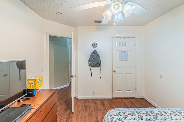 bedroom featuring dark wood-type flooring, ceiling fan, and a textured ceiling