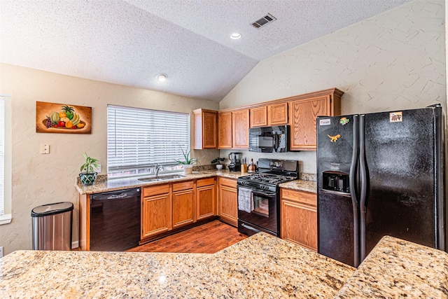 kitchen featuring dark hardwood / wood-style floors, lofted ceiling, sink, black appliances, and a textured ceiling