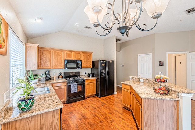 kitchen featuring a chandelier, a center island, vaulted ceiling, light stone countertops, and black appliances