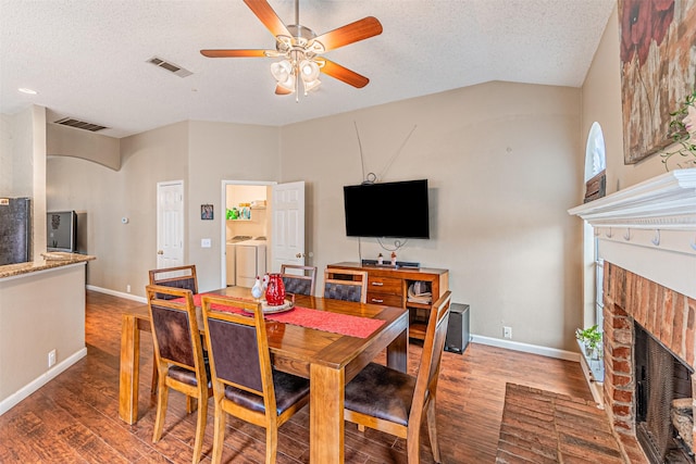 dining area featuring hardwood / wood-style flooring, a brick fireplace, washer and dryer, and a textured ceiling