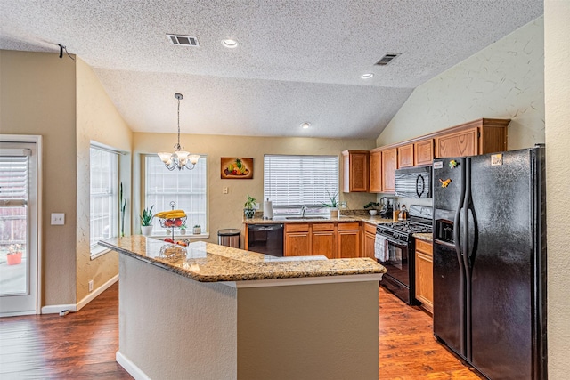 kitchen featuring lofted ceiling, sink, black appliances, dark hardwood / wood-style flooring, and decorative light fixtures