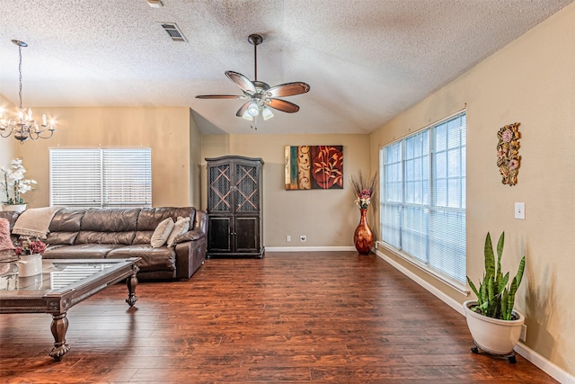 living room with lofted ceiling, ceiling fan with notable chandelier, dark hardwood / wood-style floors, and a textured ceiling