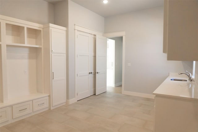 interior space with baseboards, light countertops, light wood-style floors, open shelves, and a sink