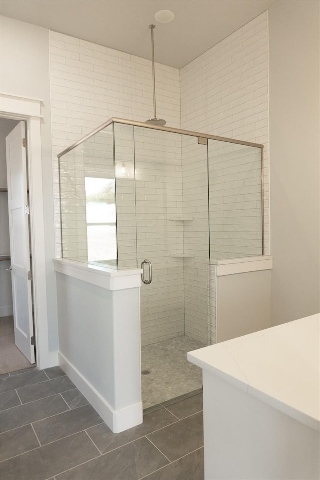 full bathroom with a stall shower, tile patterned flooring, and baseboards