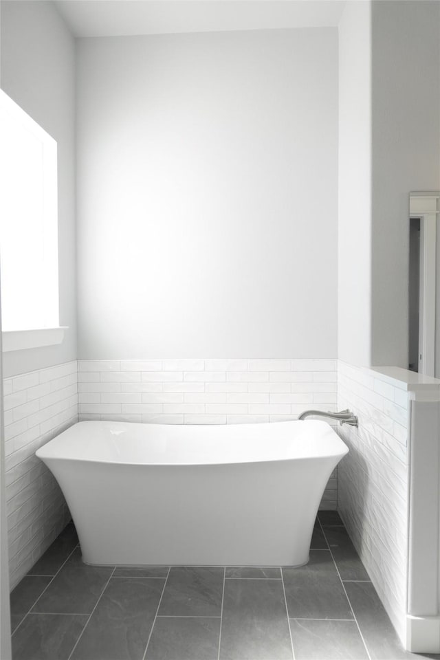 full bath featuring wainscoting, tile walls, and tile patterned floors