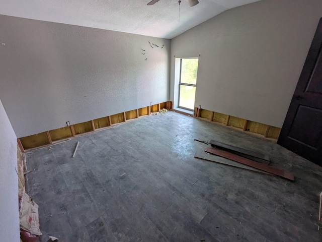 empty room featuring a textured ceiling, vaulted ceiling, a ceiling fan, and wood finished floors