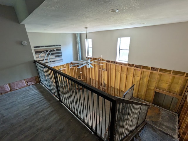 stairway with a textured ceiling and wood finished floors