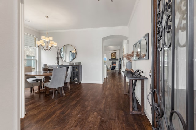 entryway featuring an inviting chandelier, a fireplace, ornamental molding, and dark hardwood / wood-style flooring