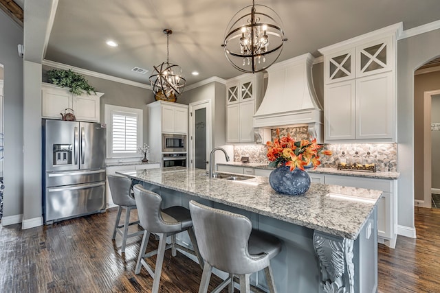 kitchen featuring pendant lighting, an island with sink, sink, stainless steel appliances, and custom range hood