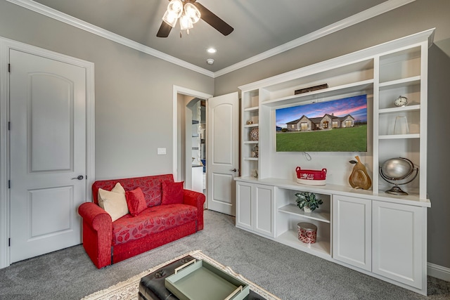 carpeted living room with crown molding and ceiling fan