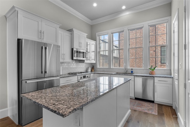 kitchen featuring sink, white cabinetry, a center island, stone counters, and stainless steel appliances