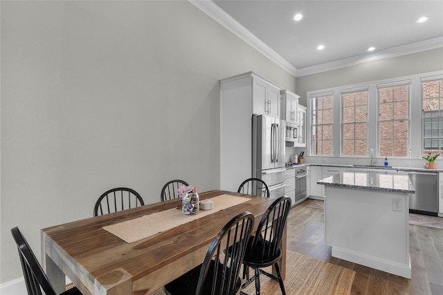 dining room with crown molding, sink, and light hardwood / wood-style flooring