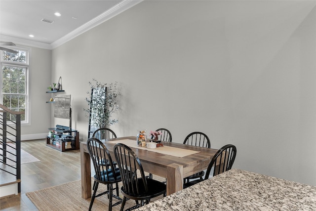 dining room with crown molding and light hardwood / wood-style flooring