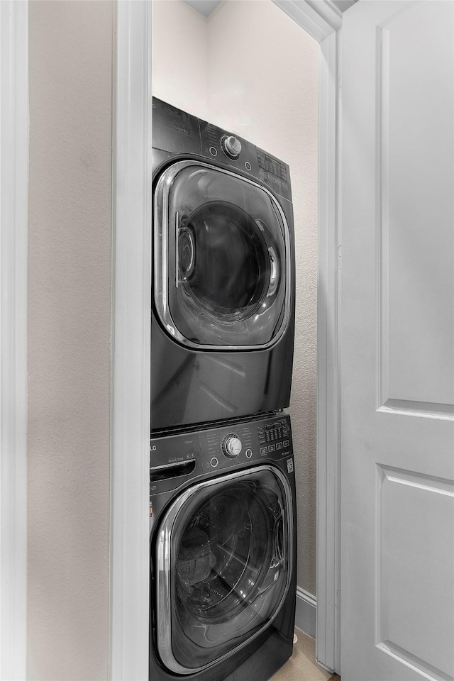 washroom featuring stacked washer / drying machine