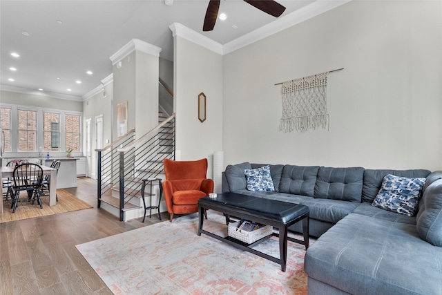 living room featuring crown molding, light hardwood / wood-style flooring, and ceiling fan