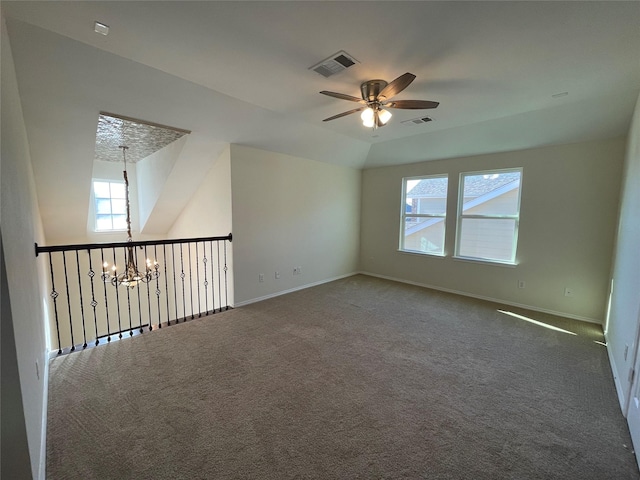 empty room featuring ceiling fan with notable chandelier, vaulted ceiling, and carpet