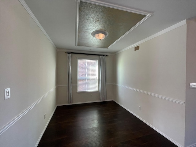 unfurnished room featuring a tray ceiling, ornamental molding, dark hardwood / wood-style floors, and a textured ceiling