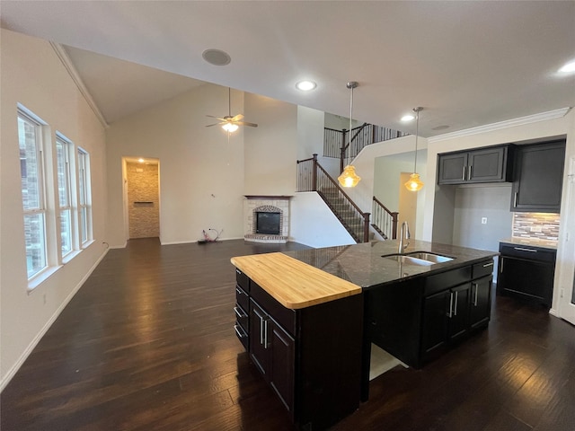 kitchen with pendant lighting, sink, dark hardwood / wood-style floors, a fireplace, and a center island with sink