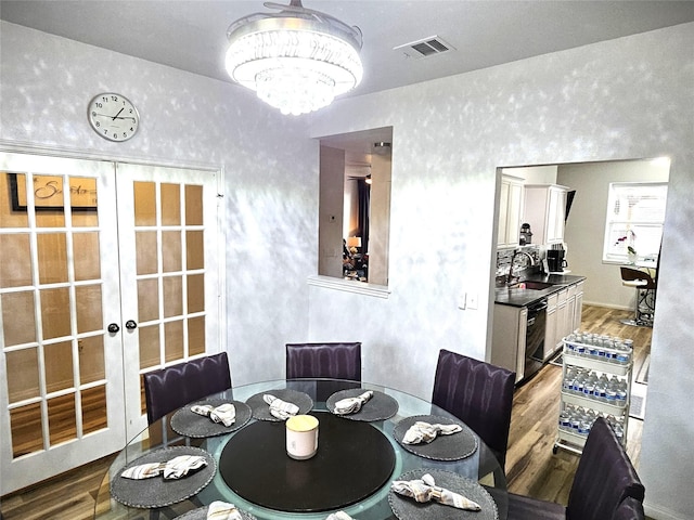 dining room featuring sink, hardwood / wood-style floors, an inviting chandelier, and french doors