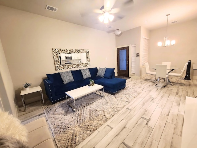 living room with ceiling fan with notable chandelier